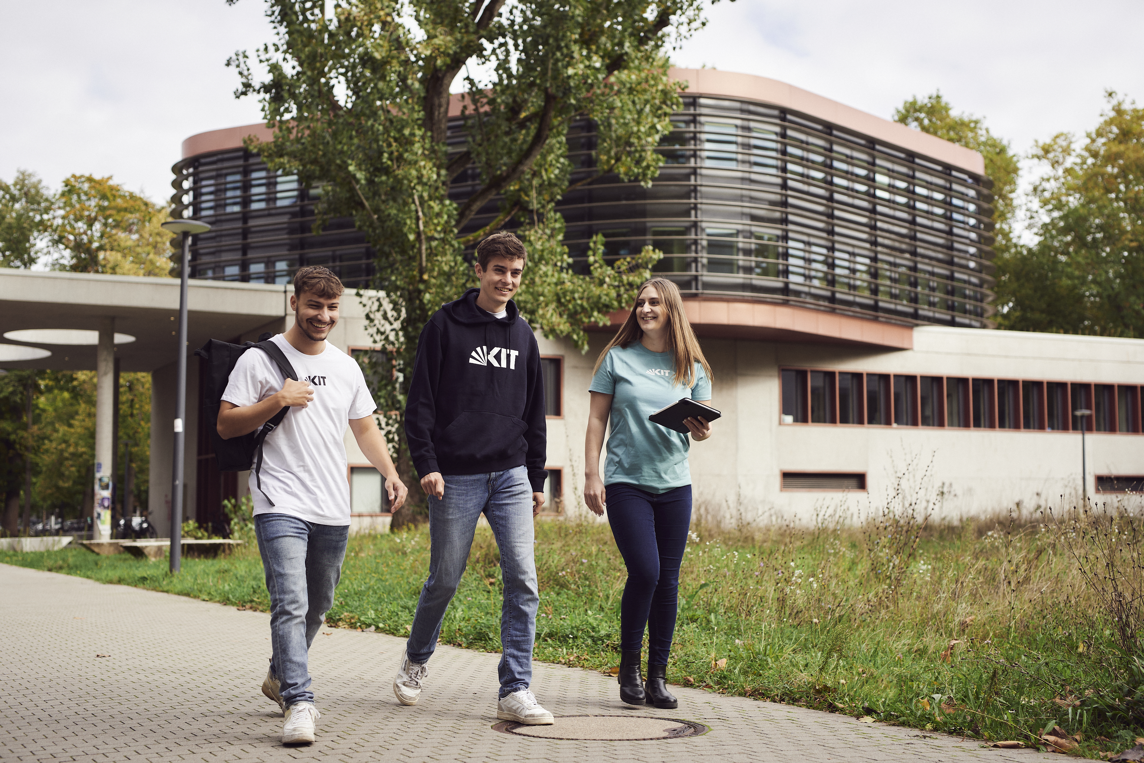 Drei studierende laufen in KIT Pullovern über den Campus
